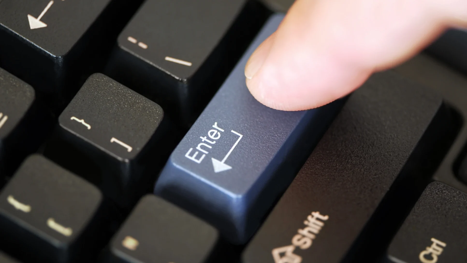 A person hitting the enter key on a keyboard.