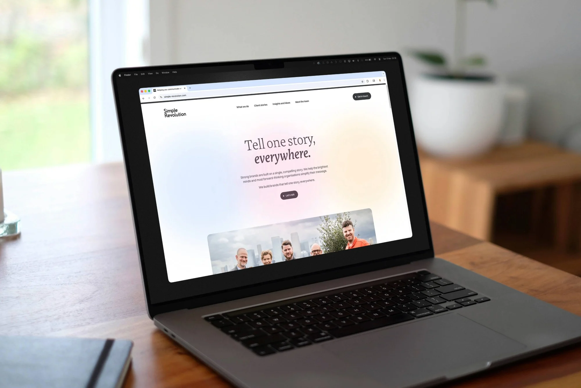 A laptop on a wooden desk with the Simple Revolution website on it.