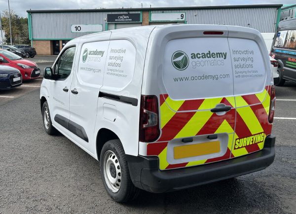 A branded Academy Geomatics van with the logo and website visible on the back doors.